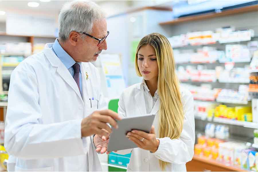 A senior pharmacist and a young pharmacist work together | 900x600